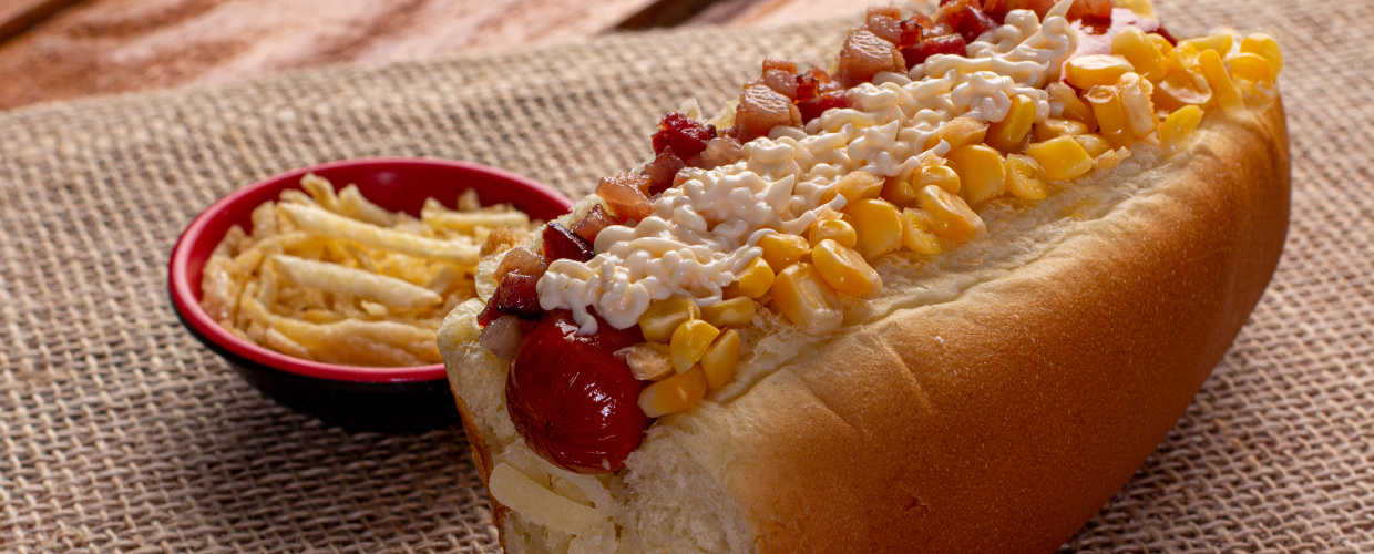 Cachorro-quente paulista e batata-palha ao lado.